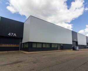 Bedrijfsgebouw met de units 47A en 47B op een bedrijventerrein onder een deels bewolkte hemel.