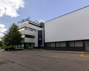 Kantoorgebouw met huisnummer 45 aan een rustige straat, met een boom en twee groene containers op de voorgrond.