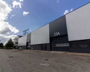 Bedrijfsgebouwen met de nummers 23A en 47B aan een rustige industriële straat onder een deels bewolkte hemel.