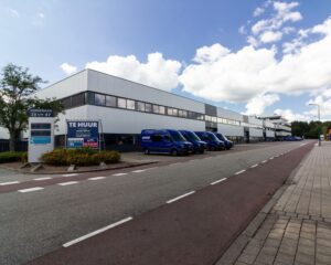 Bedrijventerrein aan de Zonnebaan met meerdere blauwe bestelbusjes en een gebouw met kantoorruimte te huur.