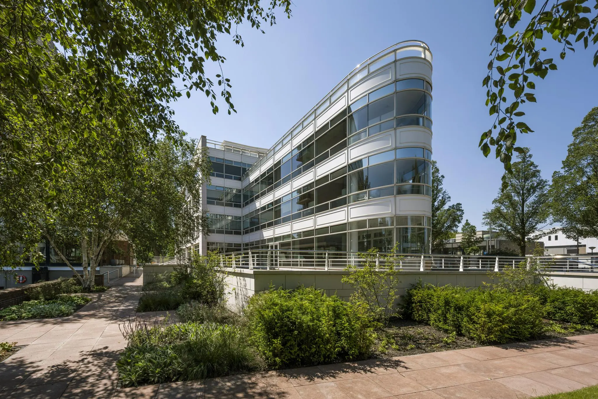 Modern kantoorpand aan de Apollolaan met glazen gevel en omliggende groene tuin.
