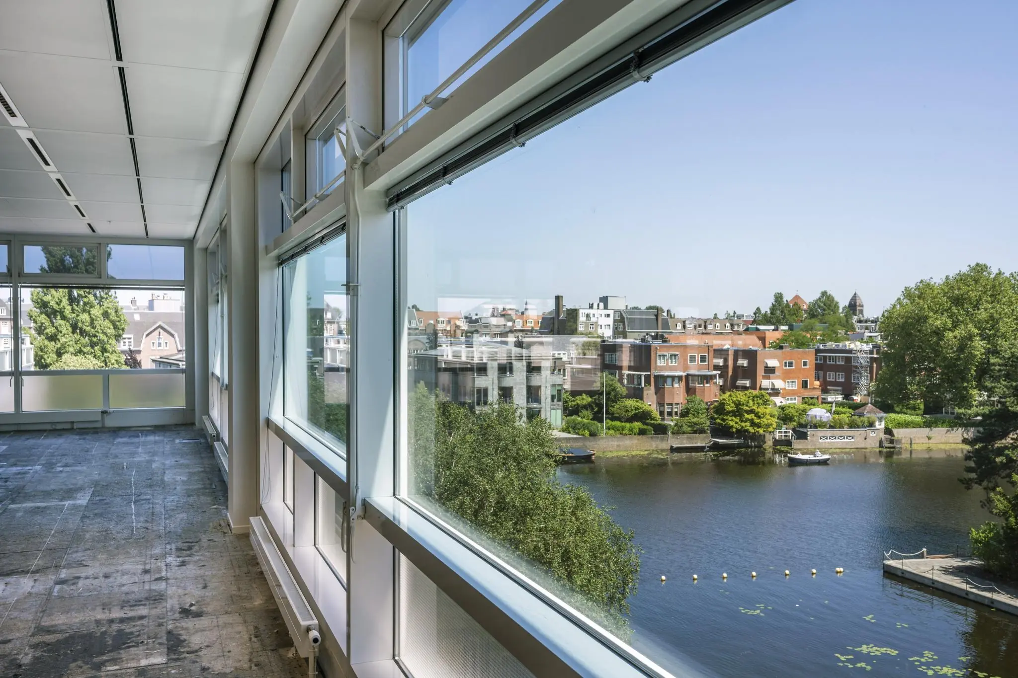 Licht en modern kantoorinterieur aan de Apollolaan met uitzicht op een gracht en omliggende woonhuizen.