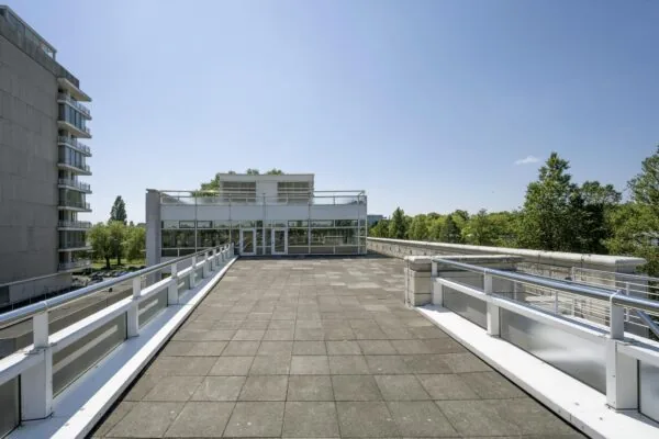 Ruim dakterras met wit hekwerk en uitzicht op modern gebouw aan de Apollolaan in Amsterdam.