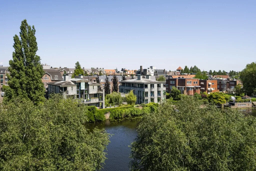 Uitzicht op moderne en klassieke woningen aan de Apollolaan in Amsterdam, gelegen langs een waterpartij met omliggend groen.