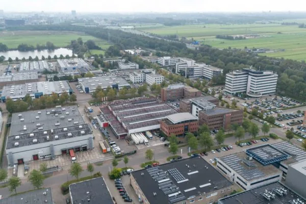 Luchtfoto van bedrijventerrein Veldzigt met kantoren, magazijnen en parkeerplaatsen omringd door groen en weilanden.