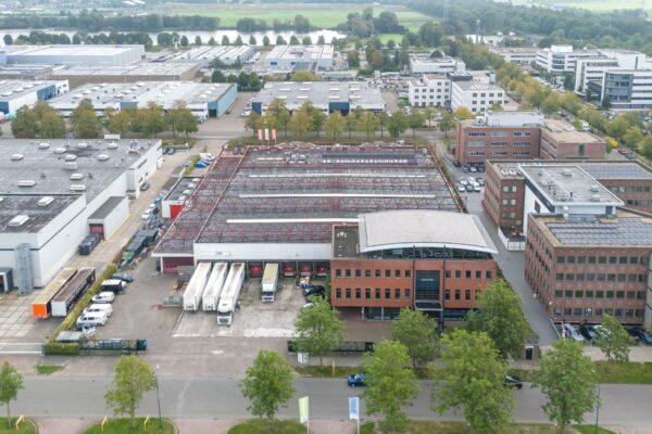 Luchtfoto van bedrijventerrein Veldzigt met kantoren, loodsen en vrachtwagens.