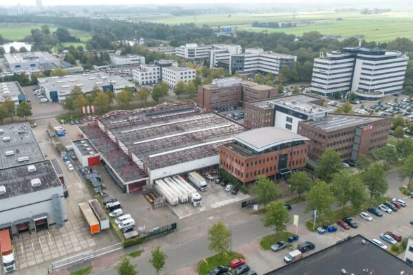 Luchtfoto van bedrijventerrein Veldzigt met kantoren, magazijnen en geparkeerde voertuigen in een groene omgeving.