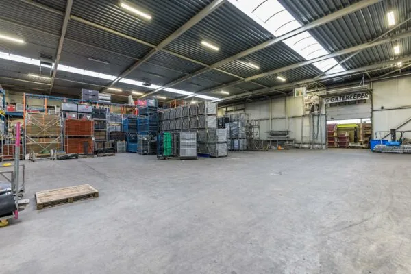 Ruime en nette opslagloods van Veldzigt met gestapelde metalen rekken en het bord "Gatekeeper" boven een doorgang.