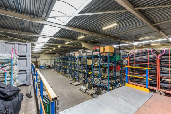 Magazijninterieur met hoge stellingen vol met metalen onderdelen en materiaal, vastgelegd bij Veldzigt.