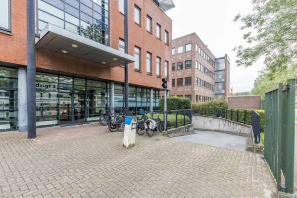 Ingang van kantoorpand Veldzigt 3 met fietsenstalling en oprit naar ondergrondse parkeergarage.