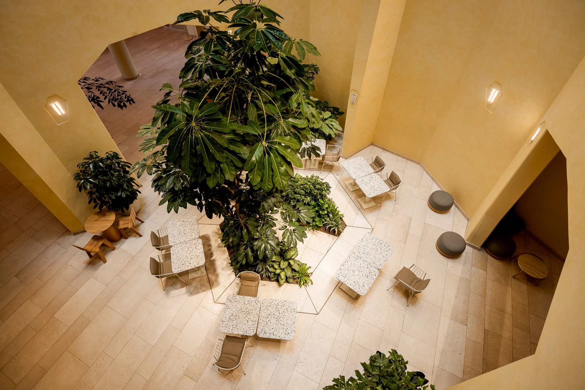 Licht atrium met terrazzo tafels, moderne stoelen en weelderige kamerplanten in Het Zandkasteel.