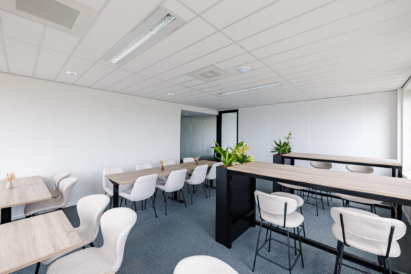 Een moderne vergaderruimte in Amersfoort met houten tafels, comfortabele stoelen en groene planten.