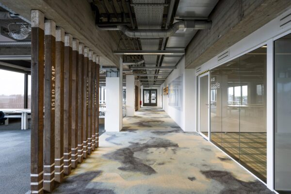 Moderne kantoorruimte in het gebouw aan de Vijzelstraat met glazen vergaderruimte, open plafondconstructie en houten decoratieve pilaren.