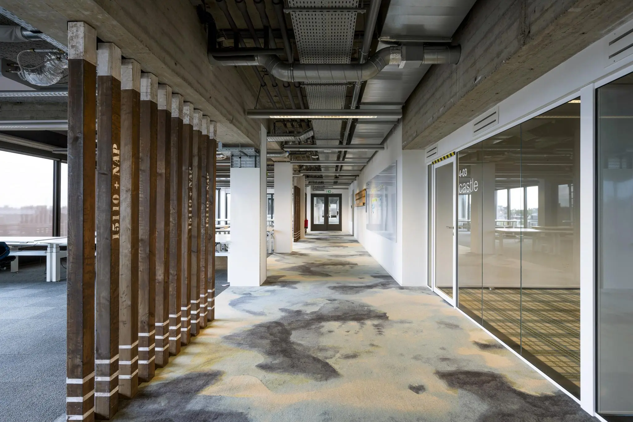 Moderne kantoorruimte in het gebouw aan de Vijzelstraat met glazen vergaderruimte, open plafondconstructie en houten decoratieve pilaren.