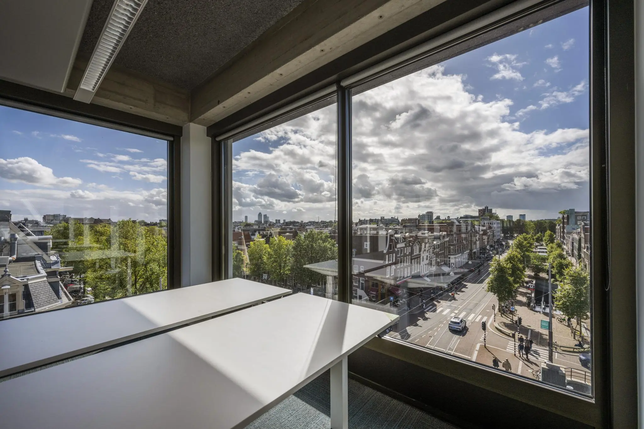 Uitzicht vanuit een modern kantoor aan de Vijzelstraat in Amsterdam met grote ramen en zicht op de stad.