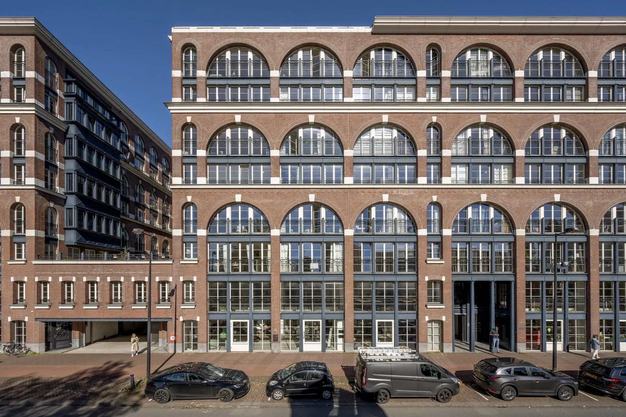 Nieuw woongebouw aan de Oostelijke Handelskade met een gevel vol grote ronde bogen en symmetrische ramen.