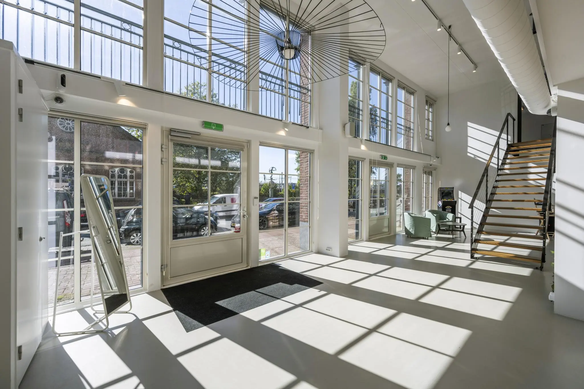 Lichte en moderne entreehal aan de Oostelijke Handelskade met hoge ramen, houten trap en zitgedeelte.