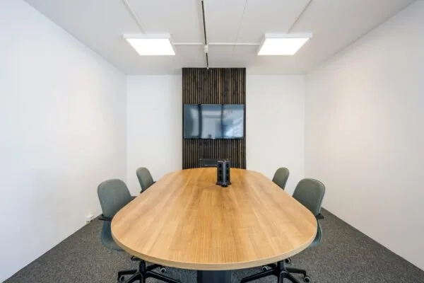 Vergaderruimte aan de Oostelijke Handelskade met ovale houten tafel, zes stoelen en een scherm aan de muur.