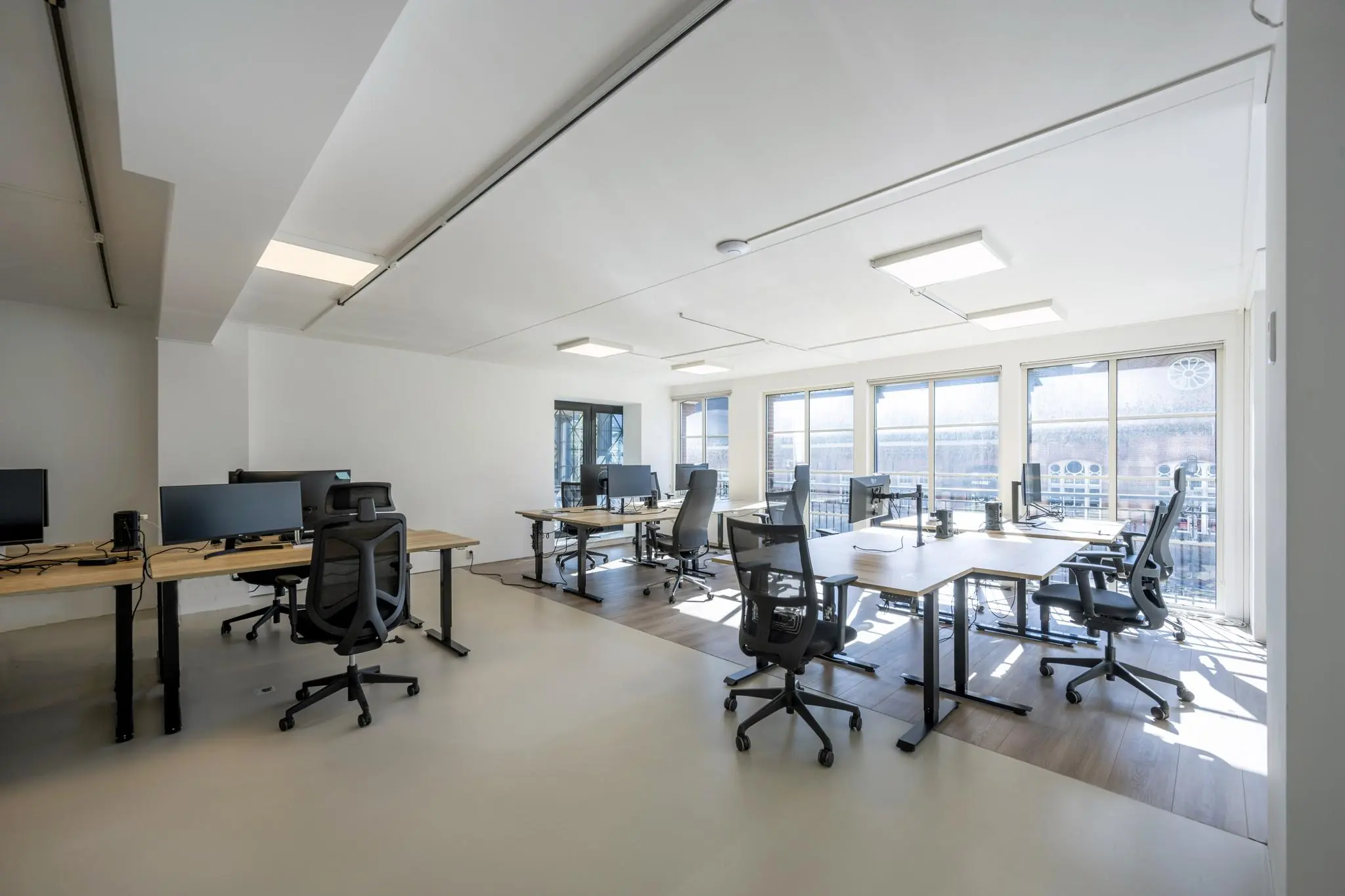 Modern en licht kantoorinterieur aan de Oostelijke Handelskade met meerdere werkplekken en grote ramen.