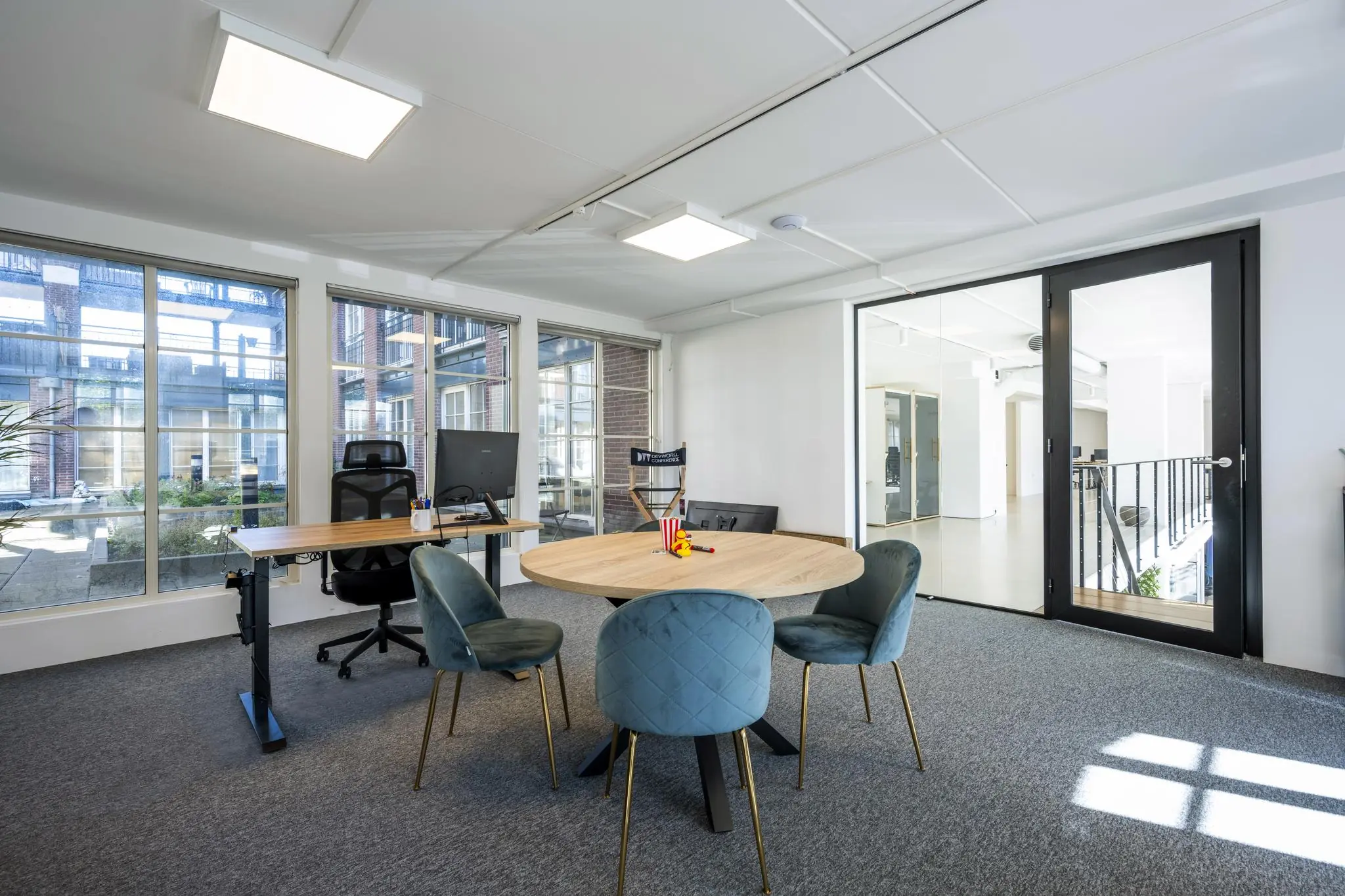 Modern kantoorinterieur aan de Oostelijke Handelskade met ronde vergadertafel, bureaustoel en grote raampartijen.