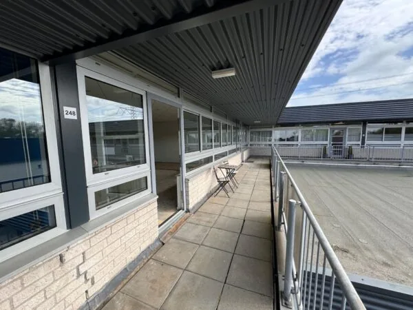 Galerij van een bedrijfs- of woongebouw aan Hoofdweg met unitnummer 248 en een klein tafeltje met twee stoelen.