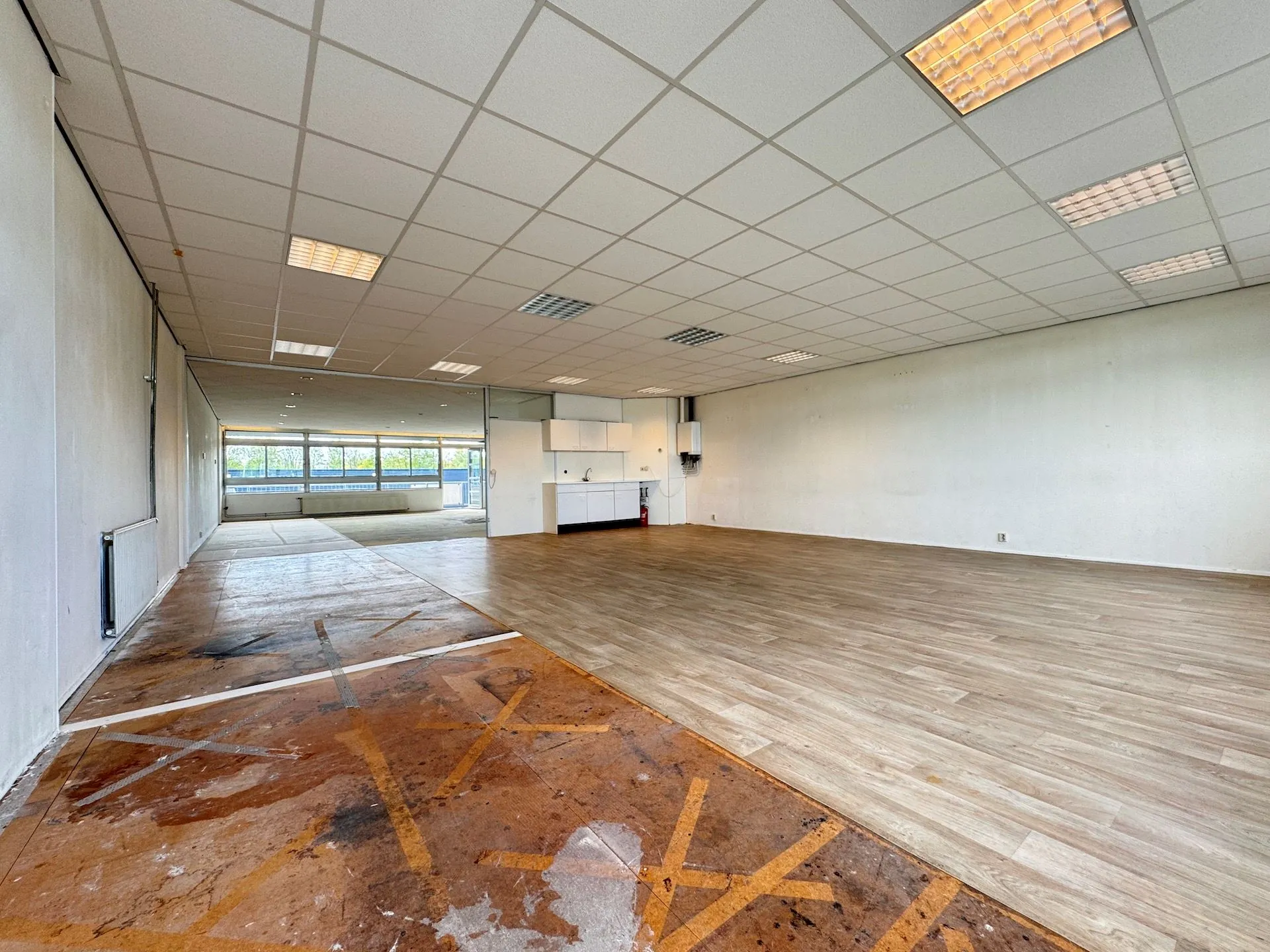 Leeg bedrijfs- of kantoorpand aan de Hoofdweg met systeemplafond, grote ramen en deels vernieuwde vloer.