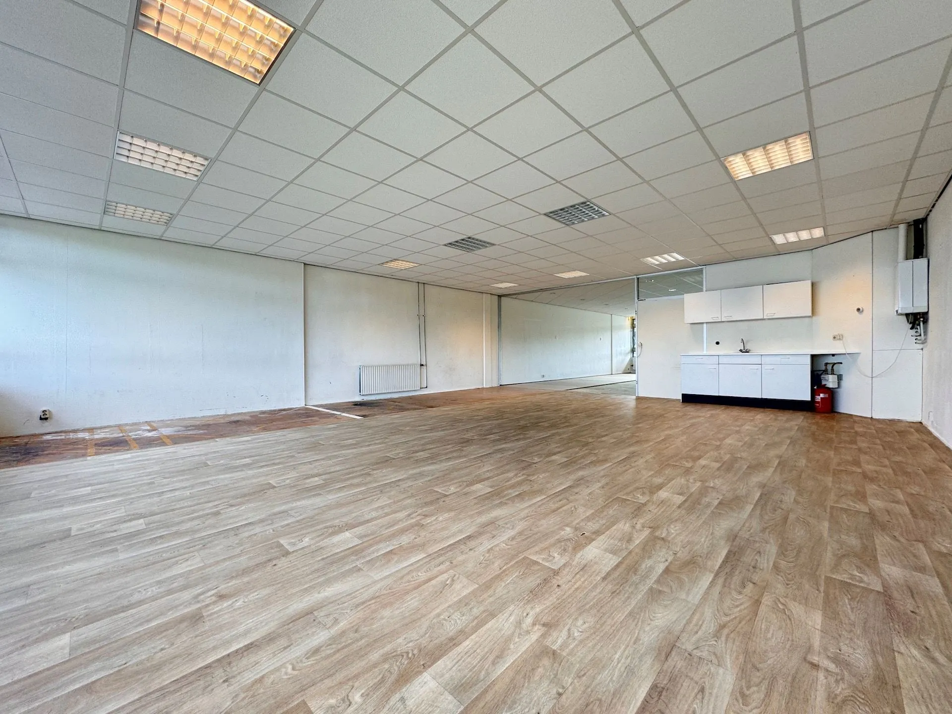 Leeg kantoorpand aan de Hoofdweg met systeemplafond, laminaatvloer en kitchenette.