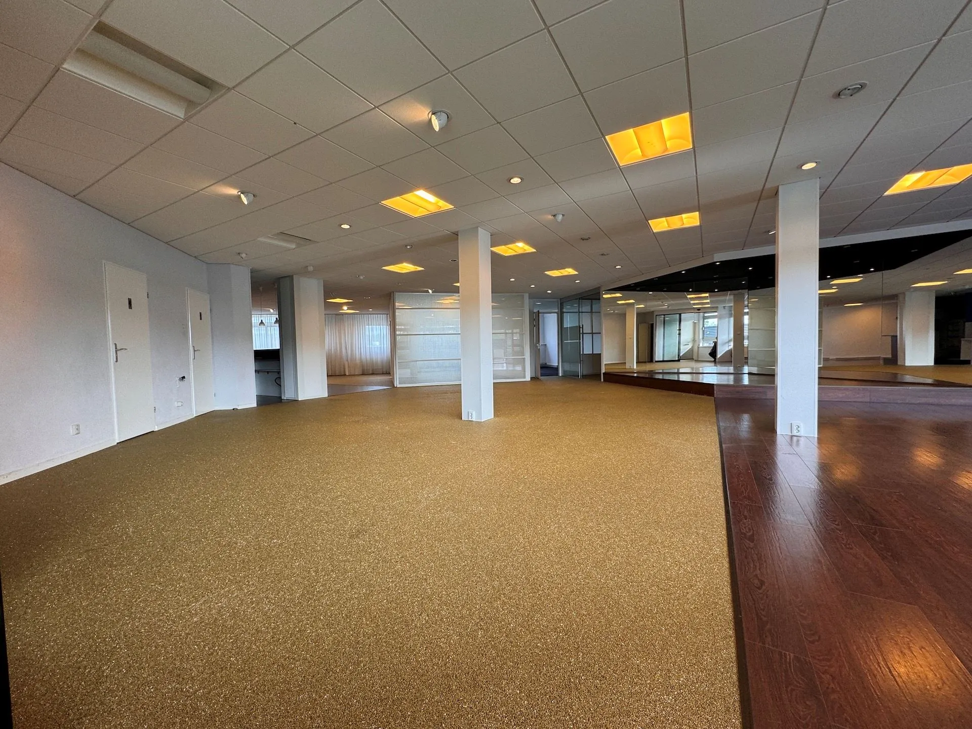 Ruime, lege commerciële ruimte aan de Hoofdweg met tapijt- en laminaatvloeren, systeemplafond en grote spiegels.
