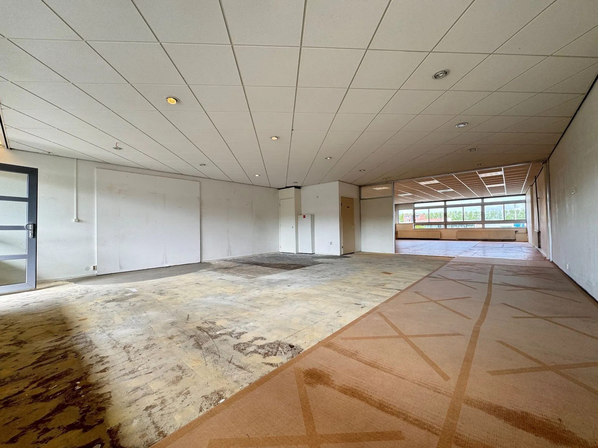 Leegstaand kantoorpand aan de Hoofdweg met gedeeltelijk verwijderde vloerbedekking en systeemplafond.