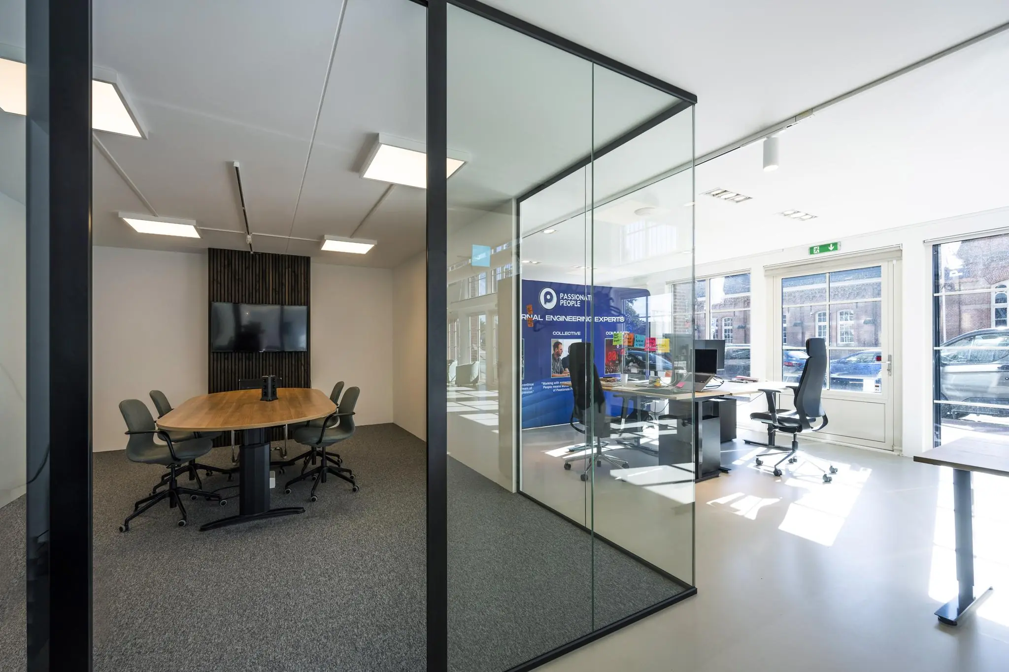 Modern kantoorinterieur aan de Oostelijke Handelskade met een glazen vergaderruimte en werkplekken bij het raam.