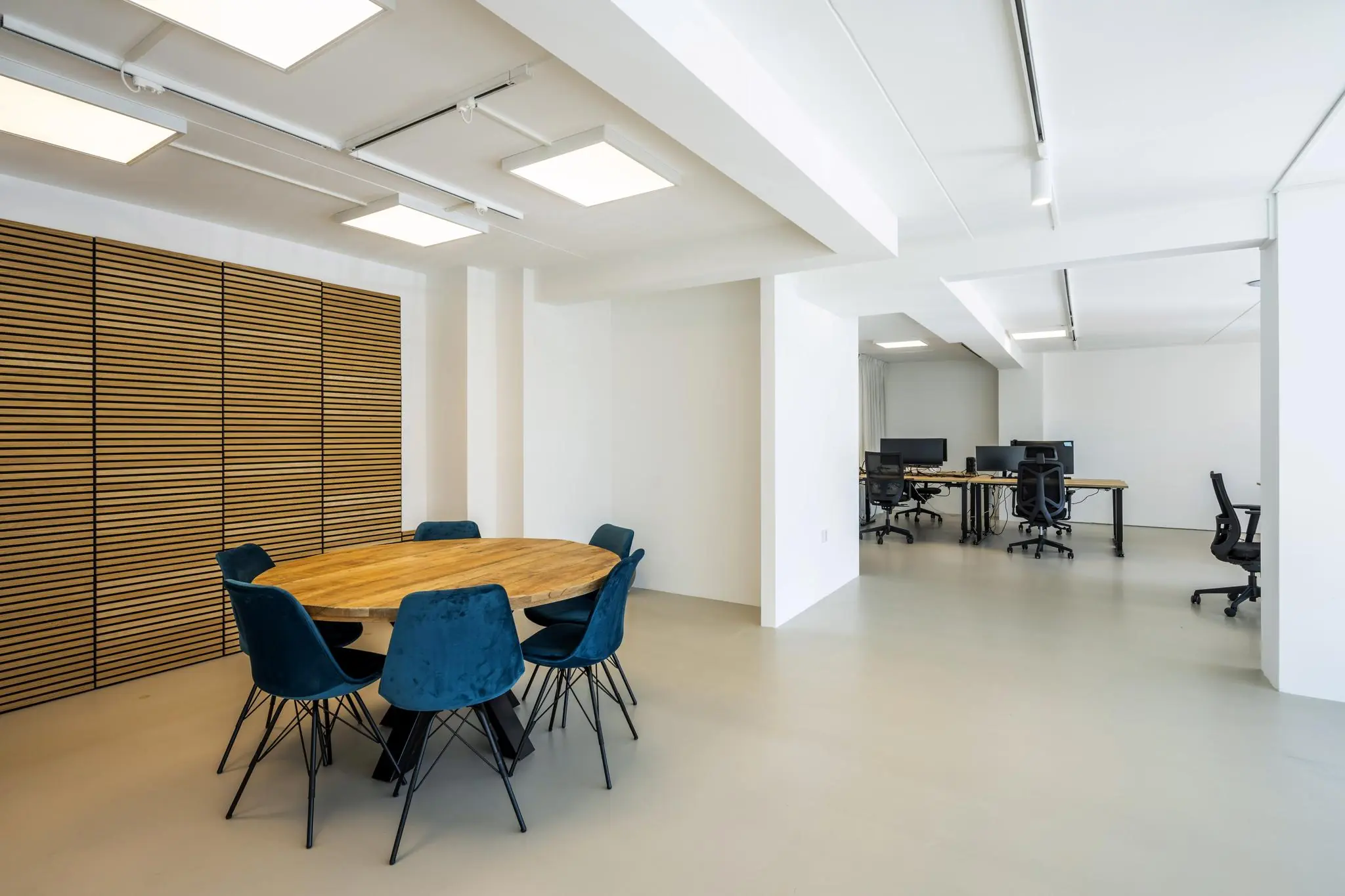 Moderne kantoorruimte aan de Oostelijke Handelskade met een ronde vergadertafel en werkplekken met bureaus en bureaustoelen.