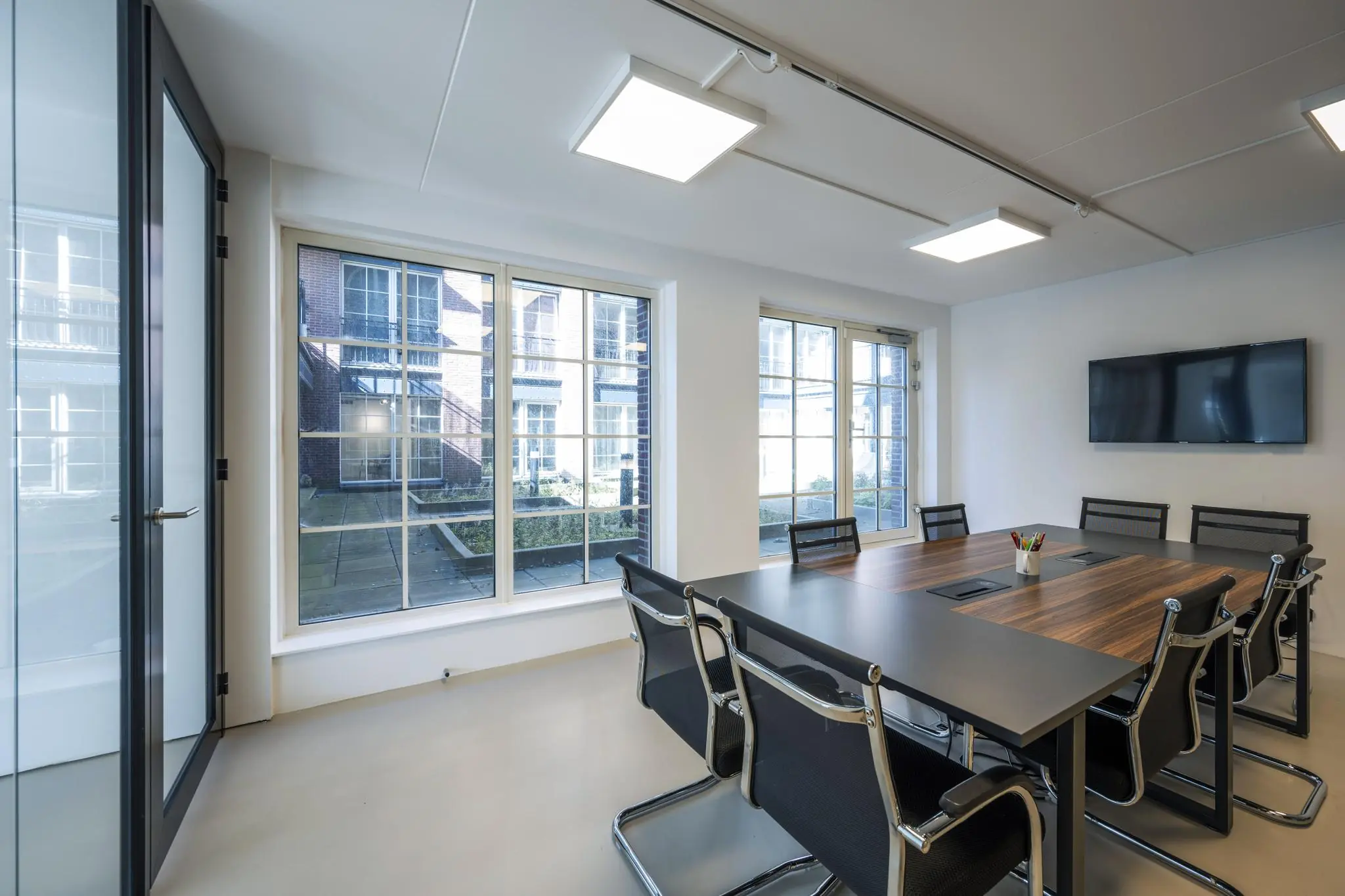 Vergaderruimte aan de Oostelijke Handelskade met grote ramen, modern meubilair en een flatscreen aan de muur.