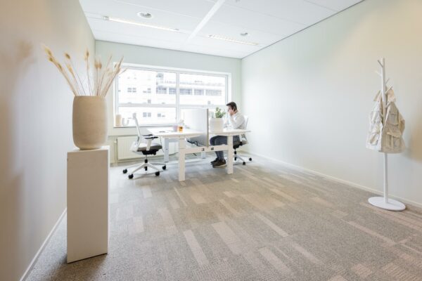 Moderne, minimalistische kantoorruimte in Rijnzathe met een man aan het werk achter een bureau bij het raam.
