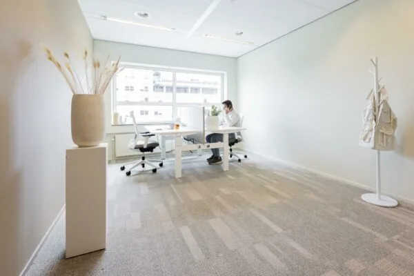 Moderne, minimalistische kantoorruimte in Rijnzathe met een man aan het werk achter een bureau bij het raam.
