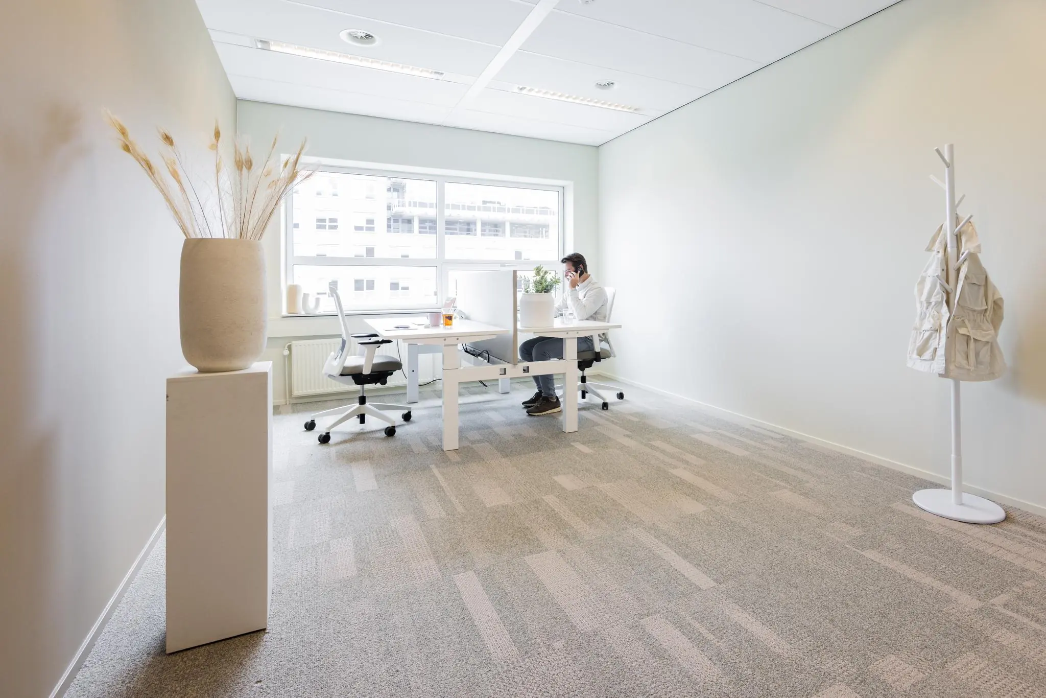 Moderne, minimalistische kantoorruimte in Rijnzathe met een man aan het werk achter een bureau bij het raam.