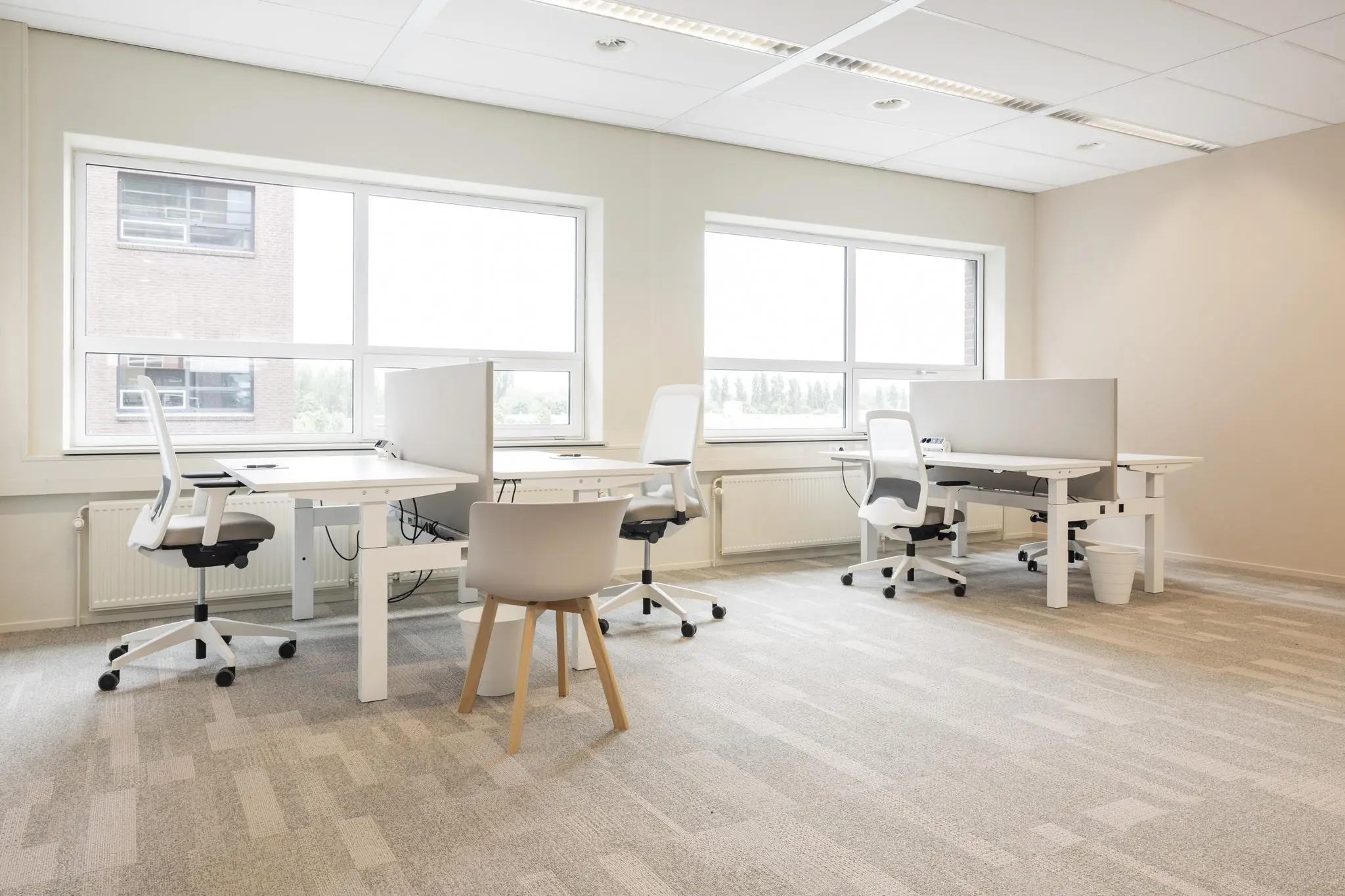 Licht en modern kantoorinterieur met vier werkplekken en grote ramen in Rijnzathe.