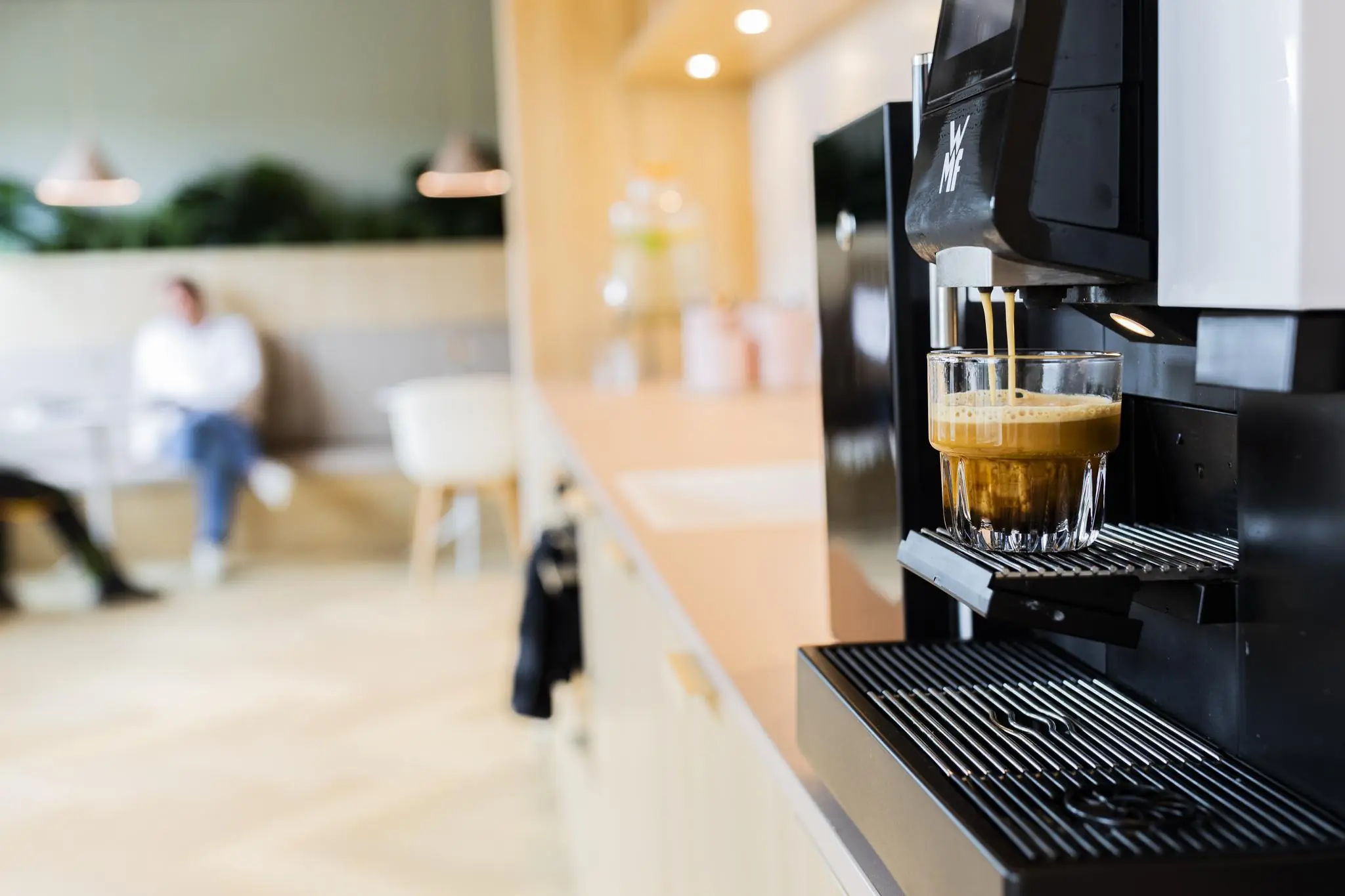 Close-up van een koffiemachine die verse koffie in een glas schenkt in een moderne kantooromgeving op Rijnzathe.
