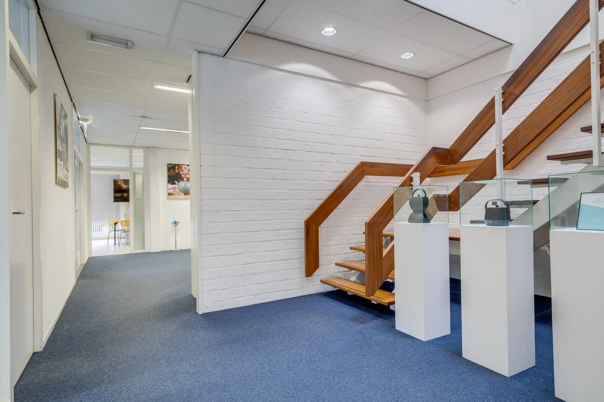 Moderne kantoorruimte aan de Savannahweg met houten trap en vitrines met designobjecten.