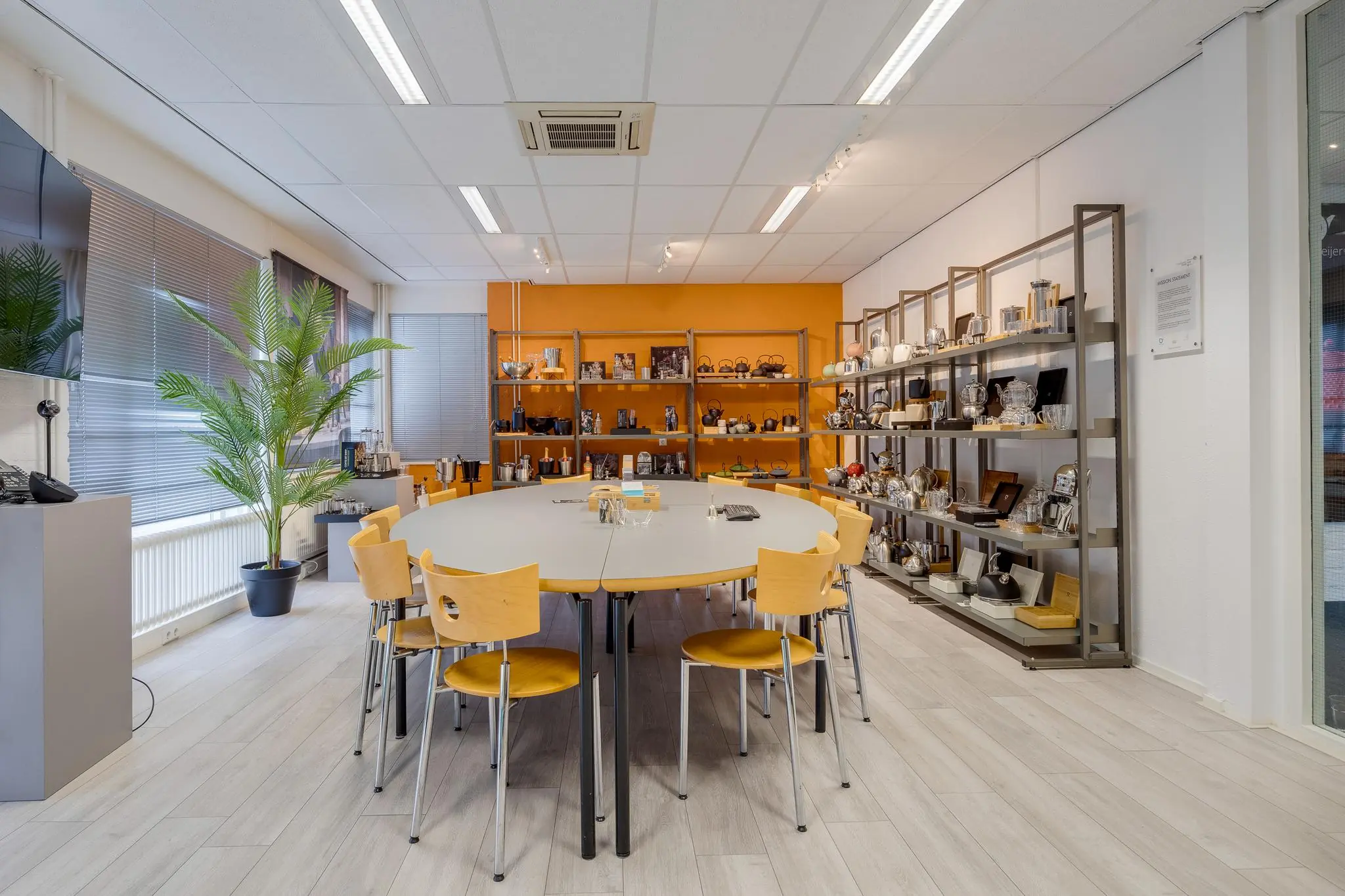 Vergaderruimte aan de Savannahweg met ovale tafel, houten stoelen en stalen stellingen vol met koffie- en theekannen.