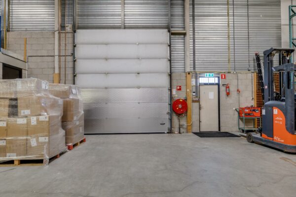 Magazijnruimte aan de Savannahweg met geladen pallets, een heftruck en een overheaddeur.