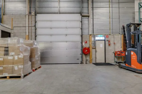 Magazijnruimte aan de Savannahweg met geladen pallets, een heftruck en een overheaddeur.