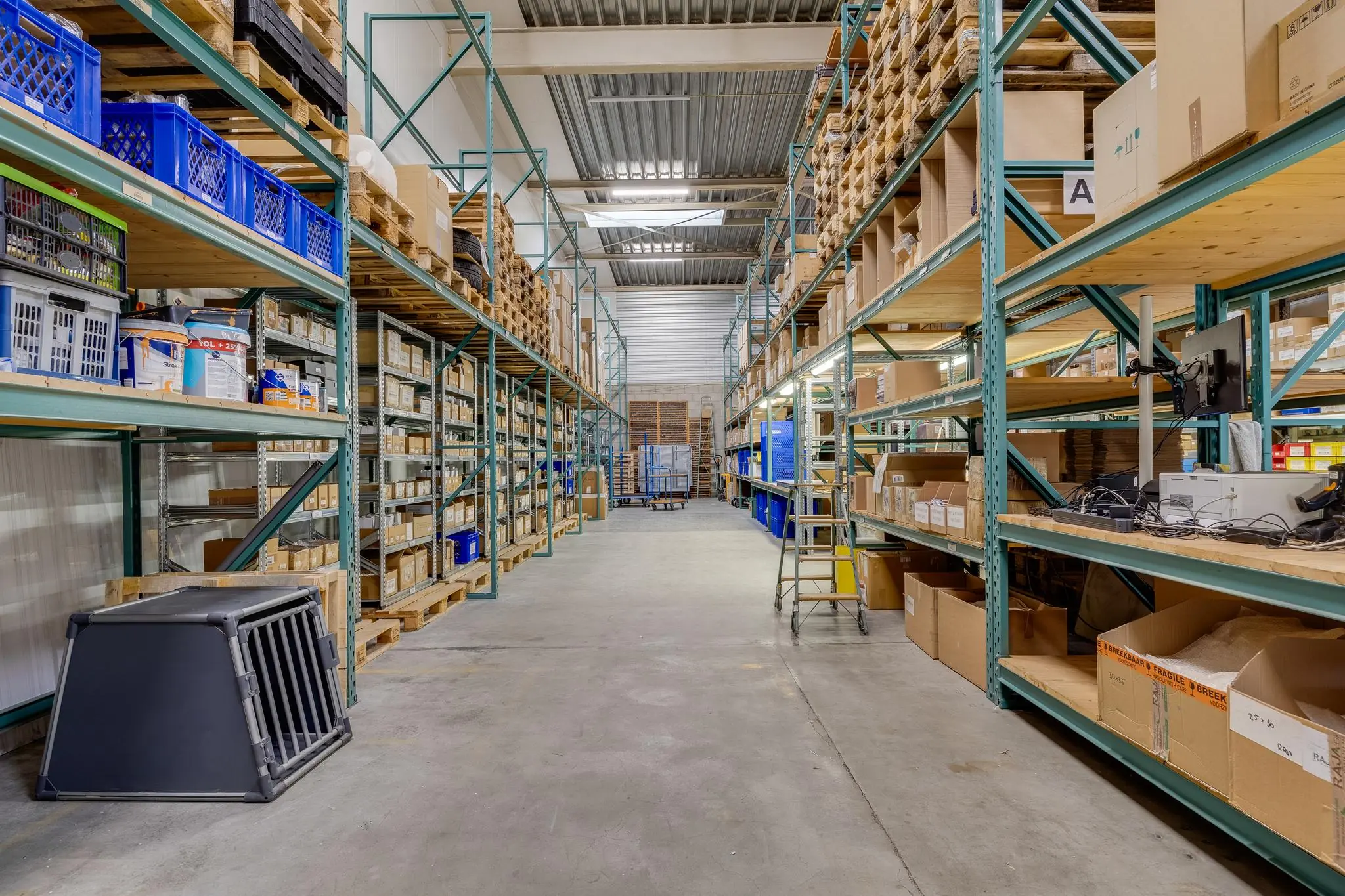 Magazijn aan de Savannahweg met hoge stellingen vol dozen, kratten en opslagmaterialen.