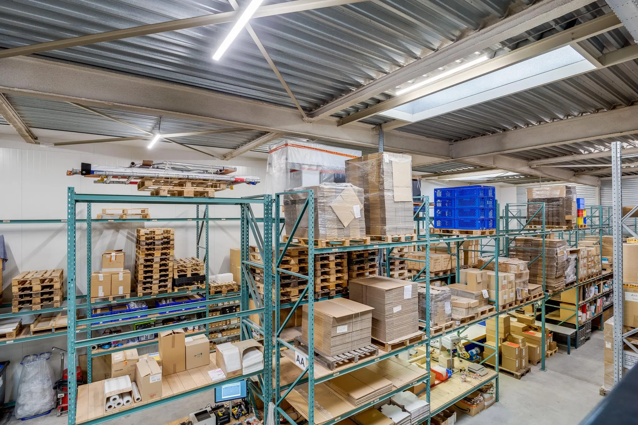 Magazijn aan de Savannahweg met stalen stellingen vol dozen, pallets en verpakkingsmateriaal.