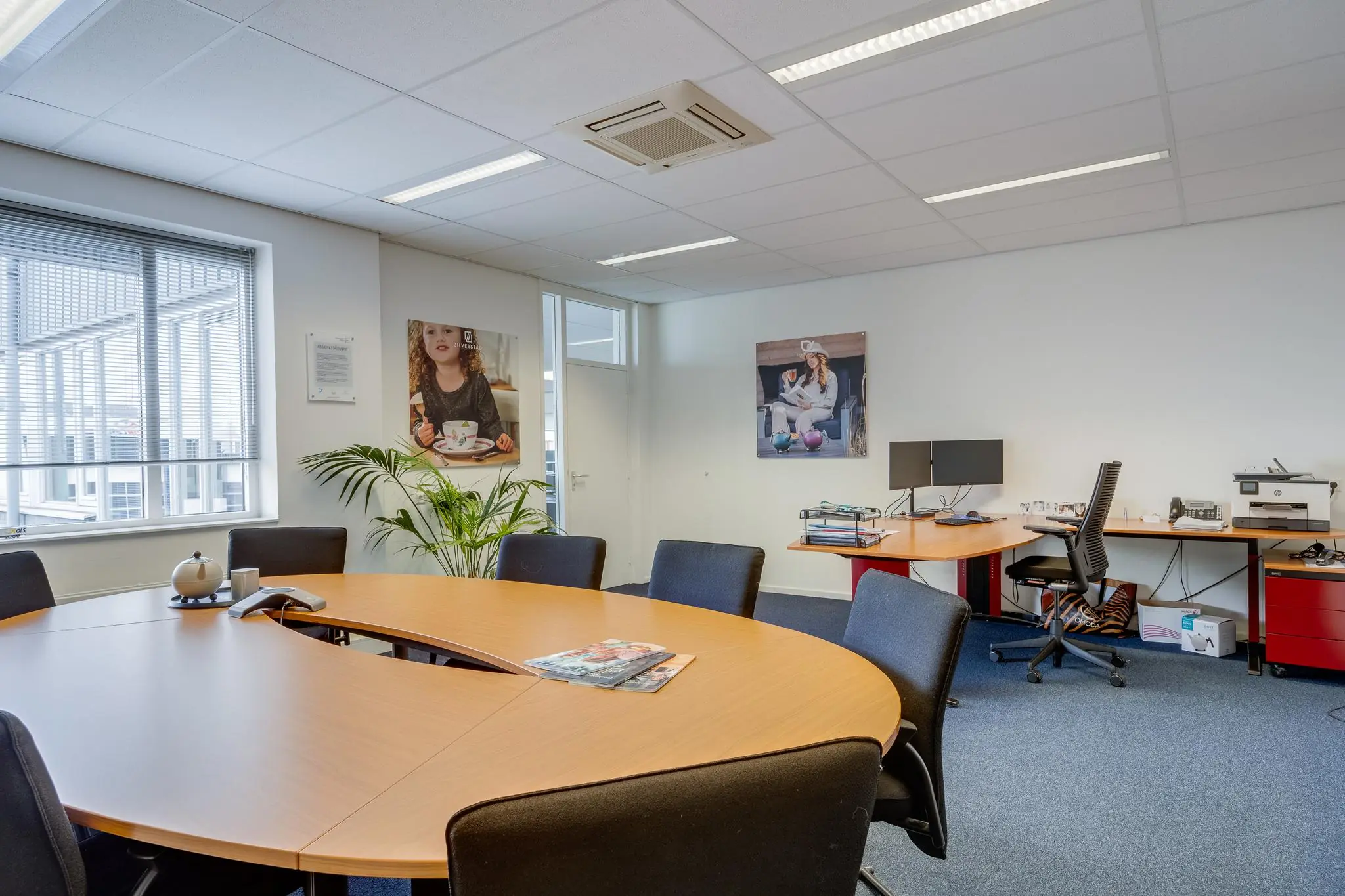 Modern kantoor met een ronde vergadertafel, bureaus, computers en wanddecoratie aan de Savannahweg.