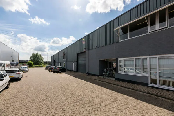 Bedrijventerrein aan de Savannahweg met geparkeerde auto's en grijze bedrijfsunits onder een deels bewolkte hemel.