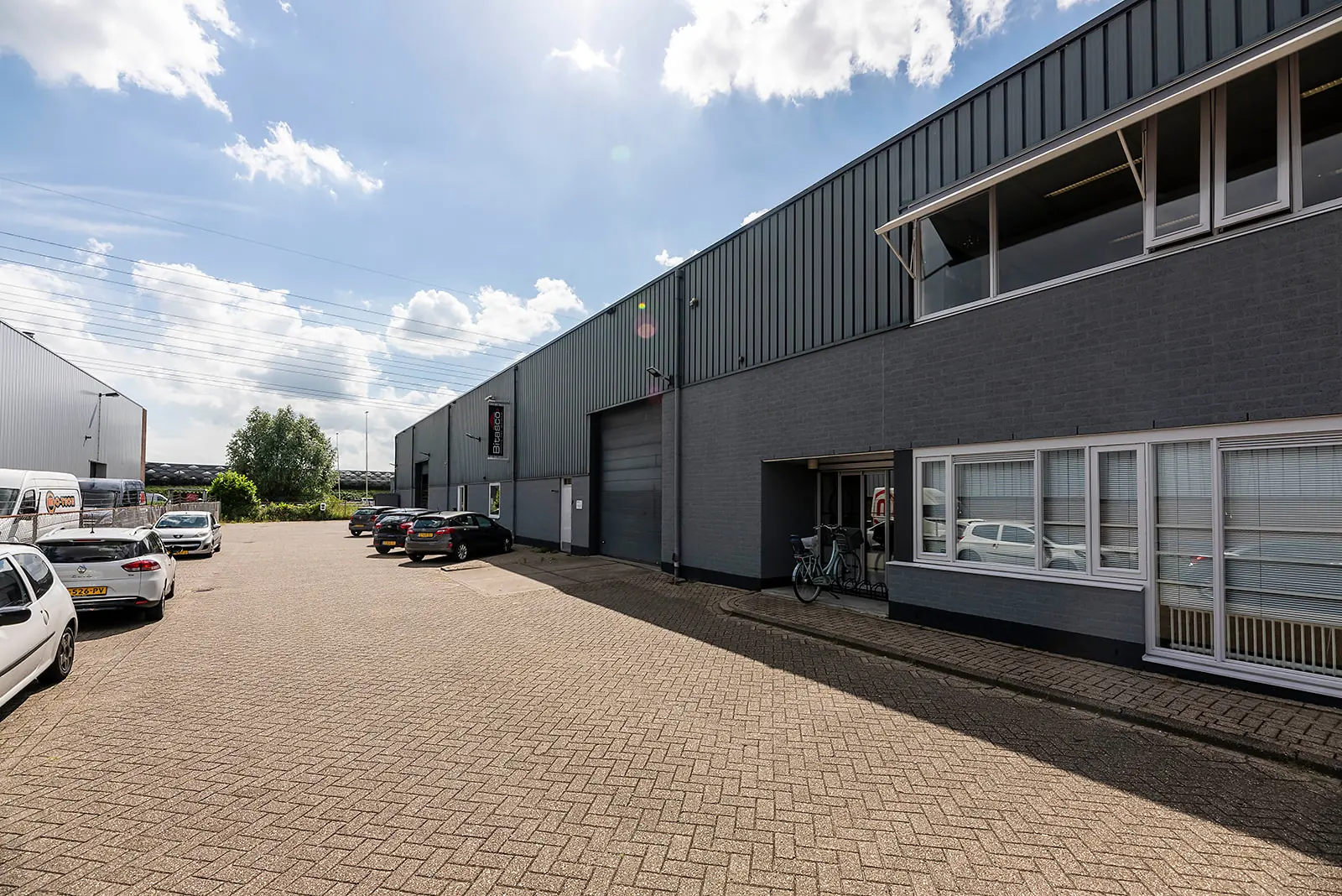 Bedrijventerrein aan de Savannahweg met geparkeerde auto's en grijze bedrijfsunits onder een deels bewolkte hemel.