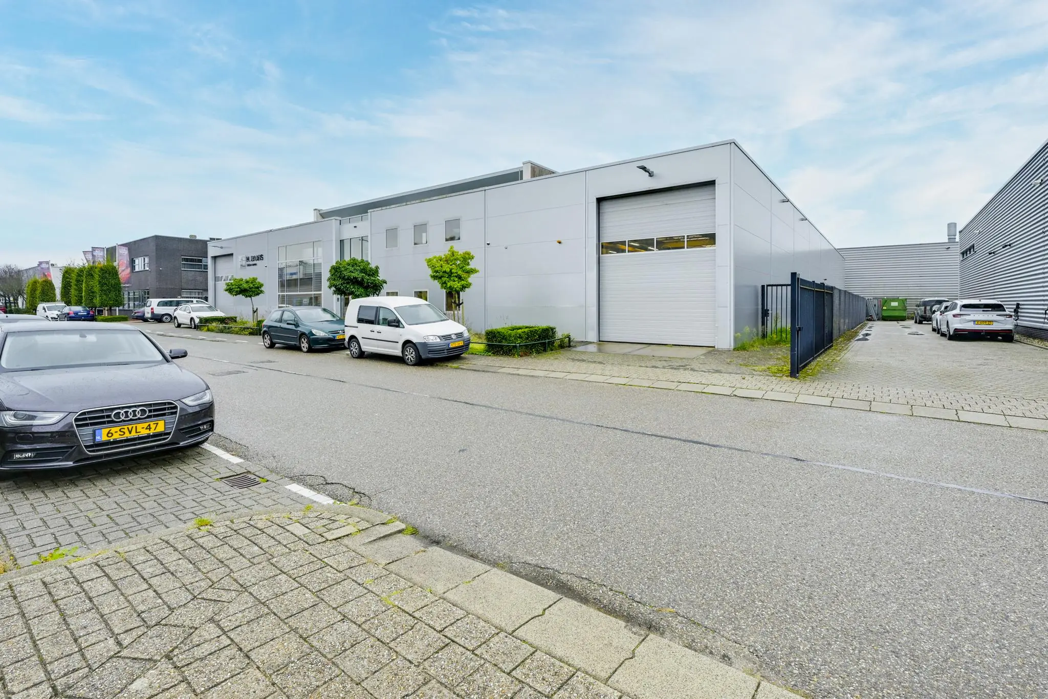 Bedrijventerrein met moderne grijze bedrijfsgebouwen aan de Tennesseedreef, met geparkeerde auto's langs de straat.