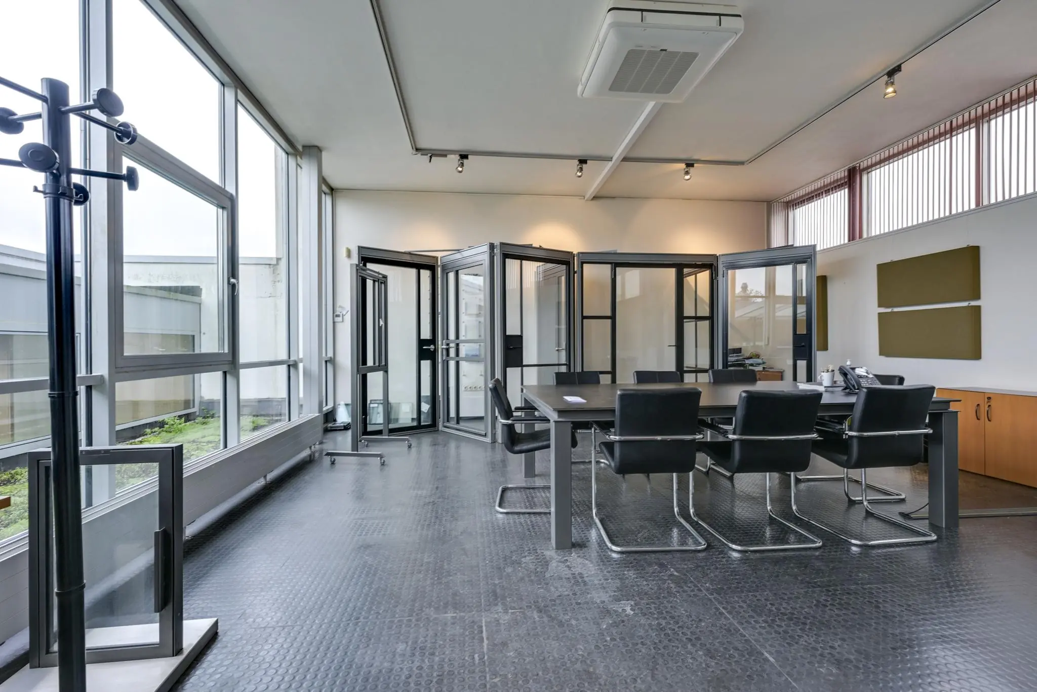 Moderne vergaderruimte aan de Tennesseedreef met glazen vouwwanden, zwarte stoelen en grote ramen.