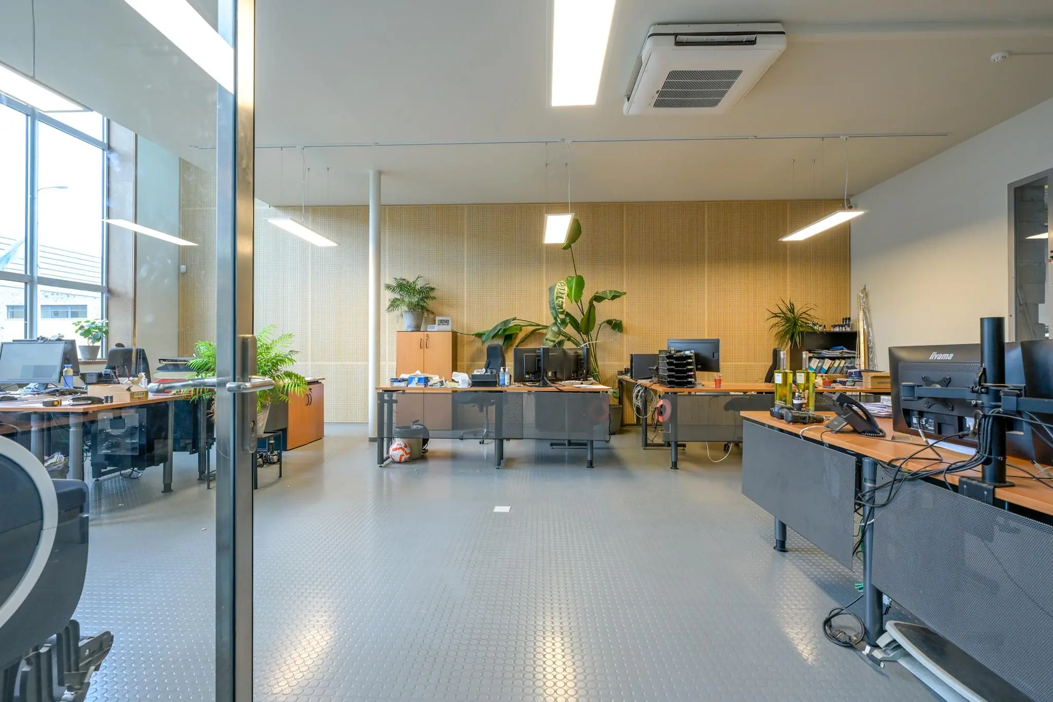 Modern kantoorinterieur aan de Tennesseedreef met meerdere bureaus, computers, kamerplanten en grote ramen.