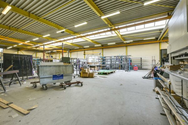 Ruime, industriële werkplaats aan de Tennesseedreef met stellingen, machines en materialen.